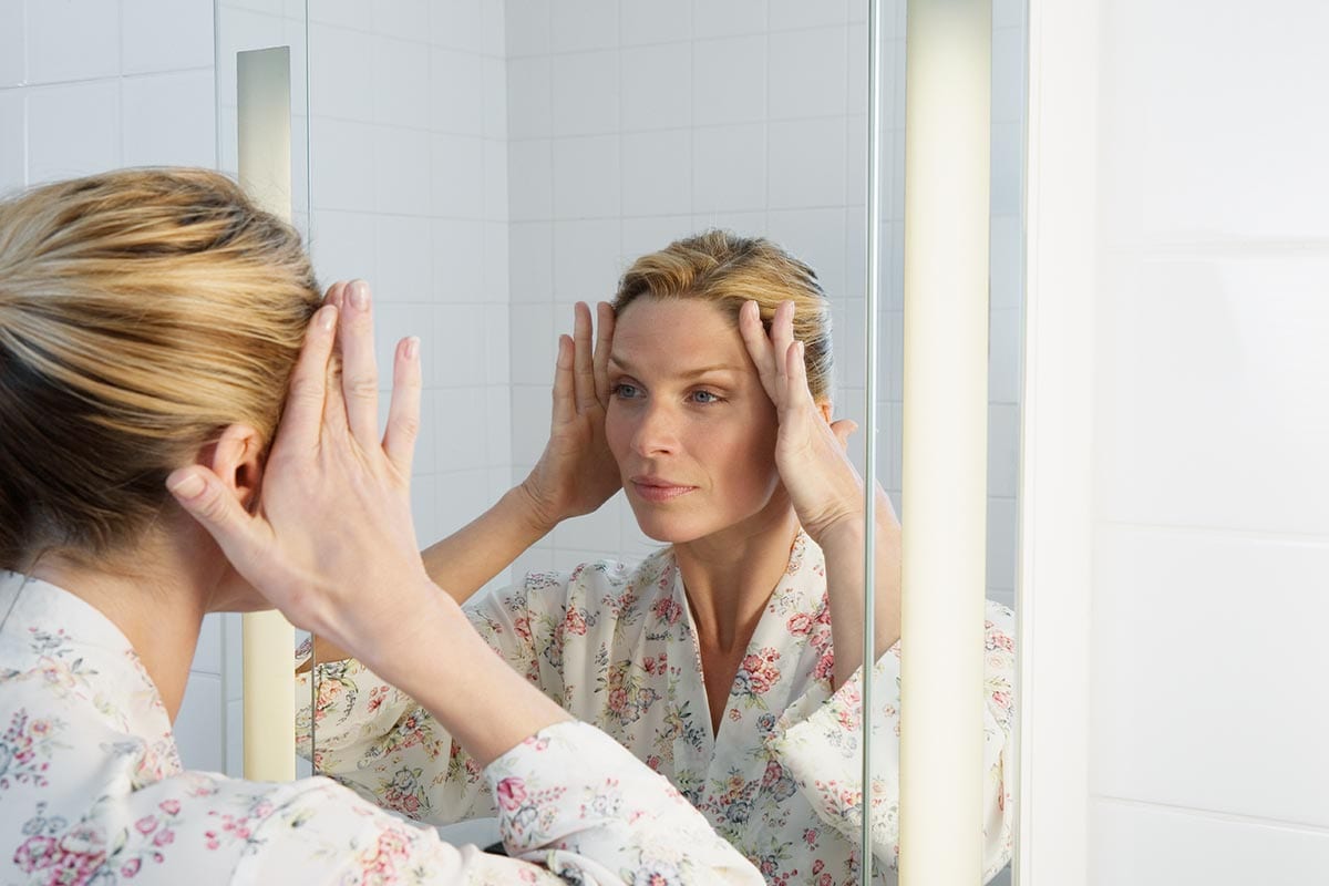 Woman smoothing out wrinkles on face with hands